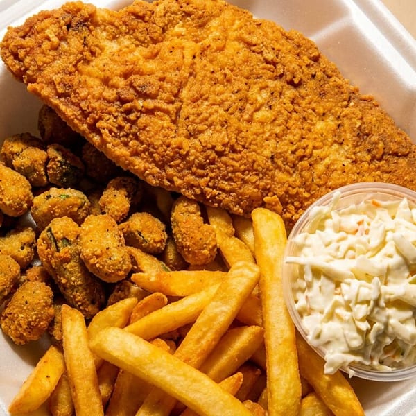 Fried fish, okra, french fries, and coleslaw in a white takeout container.